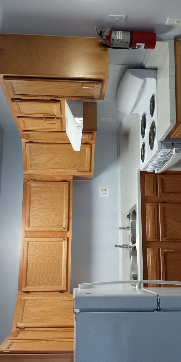a small kitchen with a refrigerator and wooden cabinets