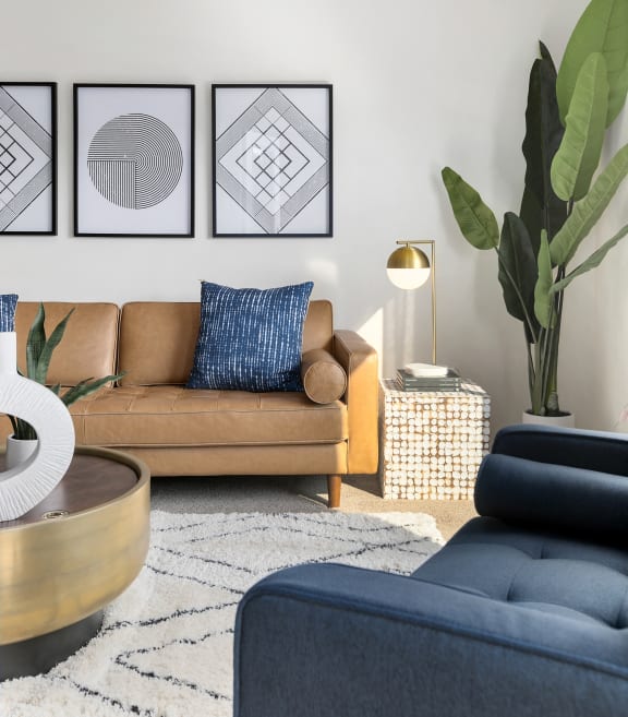 a living room with a brown couch and a blue chair  at Mosaic on the River Apartments, Richland