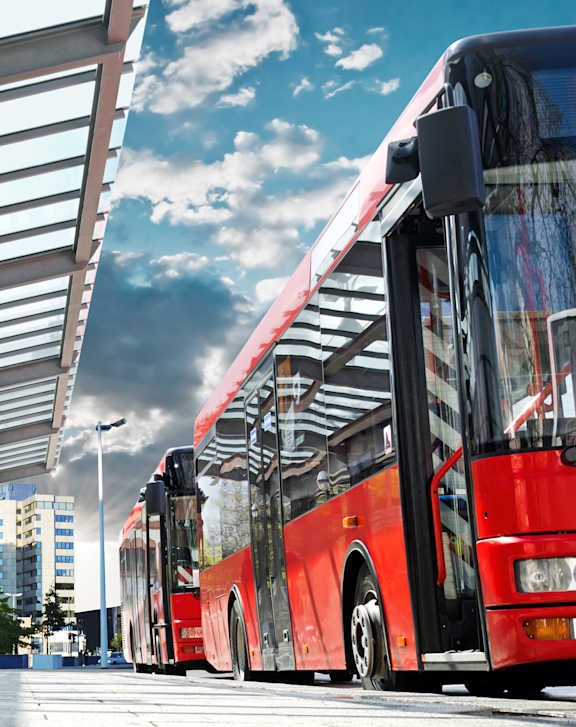 A red bus is parked at a bus stop.