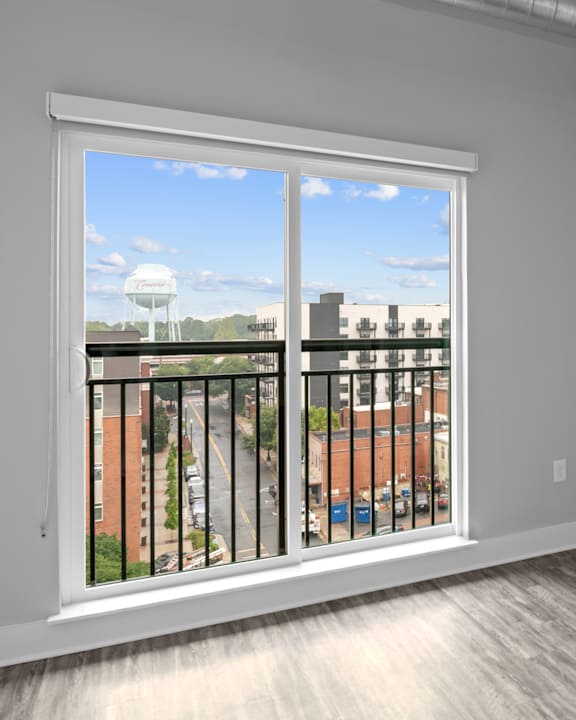 A white window with a black railing overlooking a street.
