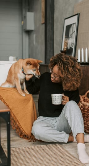 a woman sitting near a bed with a dog at Pinewood Townhomes in Tucker, Georgia