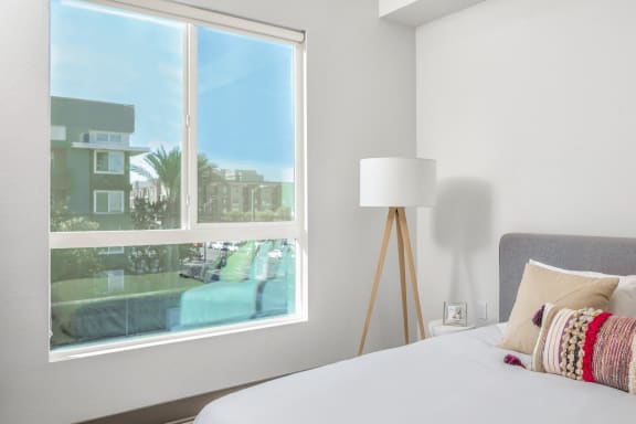 a bedroom with a large window and a bed with pillows