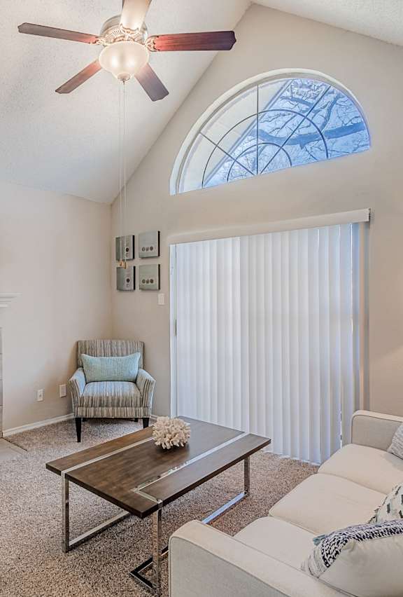 A living room with a white couch and a painting of a beach scene on the wall.