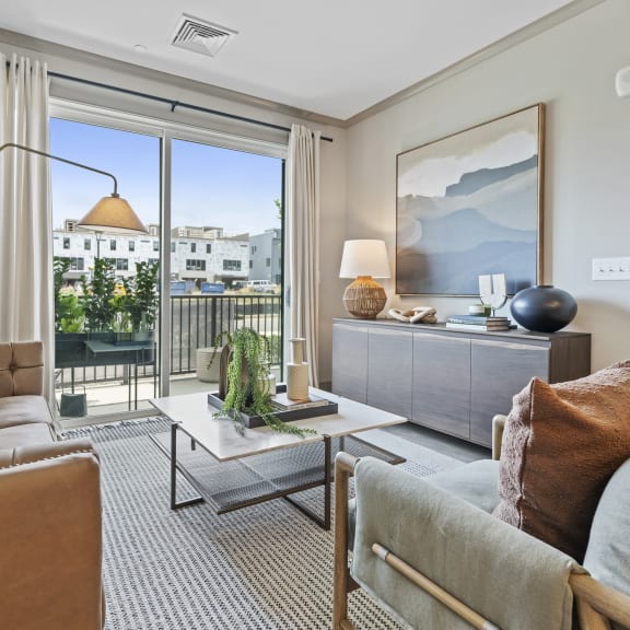 a living room with a sliding glass door that leads to a balcony at The Harrison, Newtown Square, Pennsylvania