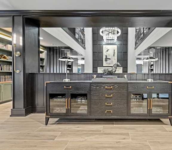 a large black credenza with gold handles and drawers in front of a large mirror