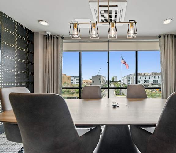 a meeting room with a table and chairs and a large window with an american flag