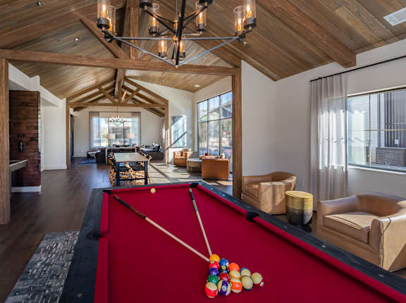 A pool table with a red cloth and a pool cue with a colorful pool ball on it.