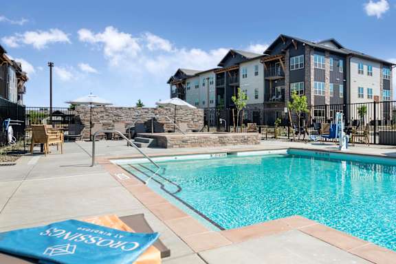 a swimming pool with lounge chairs and umbrellas at the retreat at thousand oaks apartments