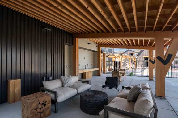 A modern outdoor living space with a wooden ceiling and black wall.
