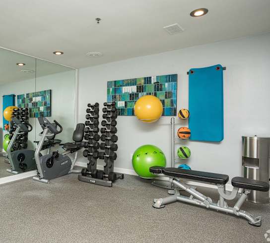 A gym with a variety of equipment including weights, exercise balls, and benches.