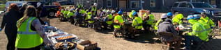 a group of people in yellow safety vests are gathered in front of a building