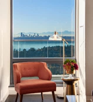 a chair and a table in front of a window with a city view at Two Lincoln Tower Apartments, Bellevue, WA, 98004