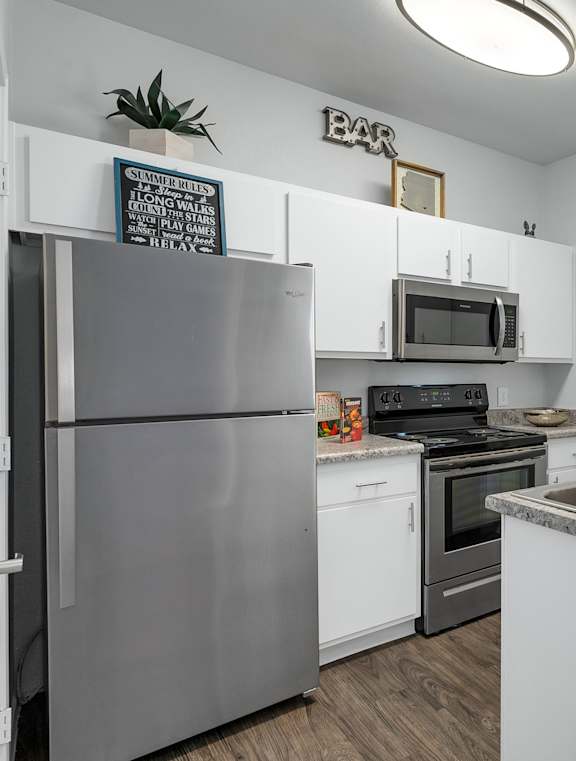 A kitchen with a refrigerator, stove, and microwave.