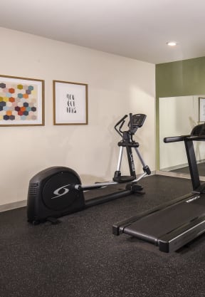 a gym with cardio equipment and a flat screen tv