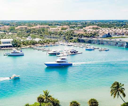 a view of a marina with boats on the water and a city in the background at Floresta, Jupiter, Florida