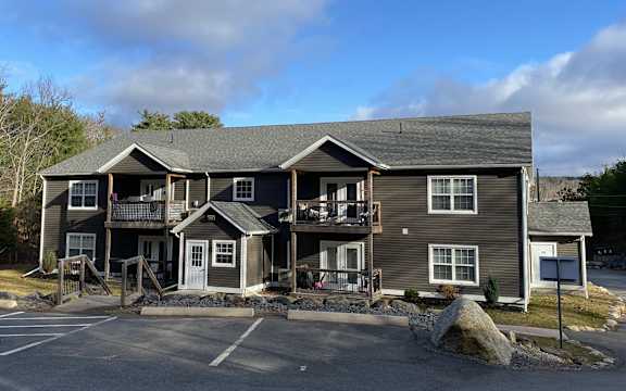 A large two-story building with a parking lot in front.