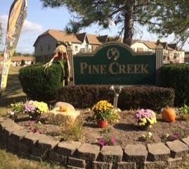 a flower garden in front of a pine creek sign
