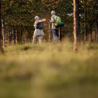 two people with backpacks walking in the woods