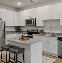 A kitchen with white cabinets and a granite countertop.