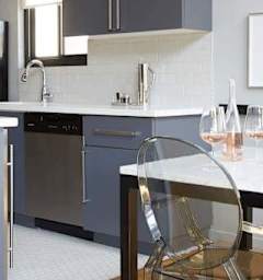 A modern kitchen with a white countertop and a glass chair.