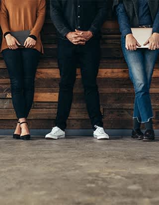 Three people standing in front of a wooden wall.
