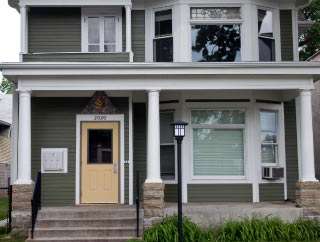 A two story house with a front porch and a yellow door.