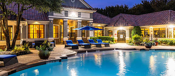 Resort-style swimming pool beside the clubhouse and leasing office building - DeLayne at Twin Creeks