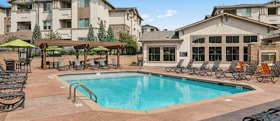 Resort-style swimming pool with ample lounge seating - First and Main Apartments