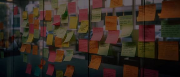 A glass wall covered with many colorful sticky notes.