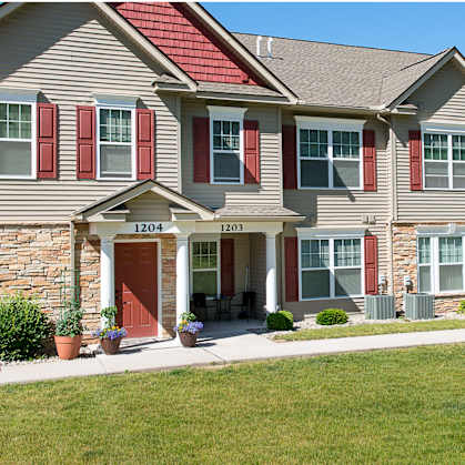 a large house with red shutters and a green lawn