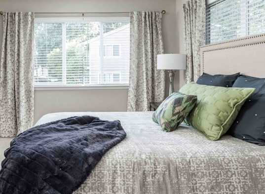 A bedroom with a bed, nightstand, and window.