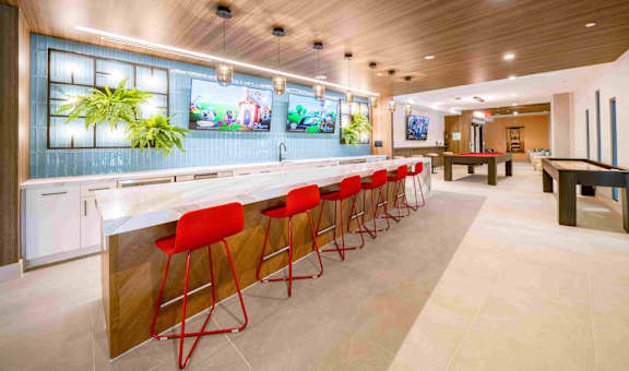 a bar with red chairs and a pool table in a lobby