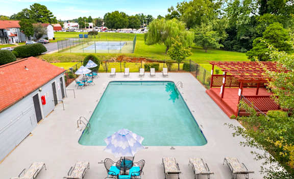 A large swimming pool surrounded by lounge chairs and umbrellas.