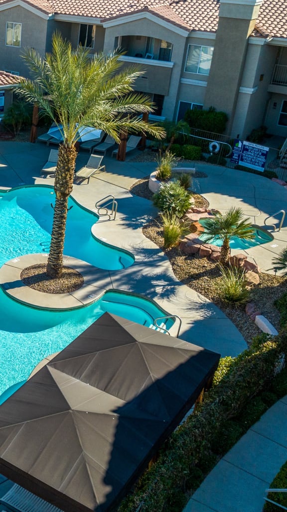 a large swimming pool with palm trees and a building in the background