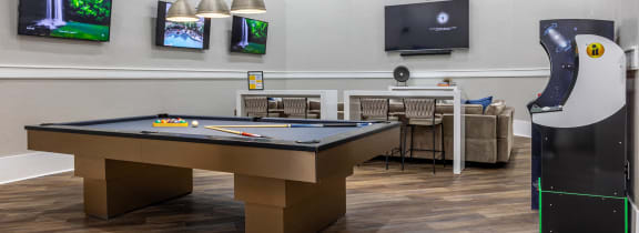 a game room with a pool table and a video game on the wall