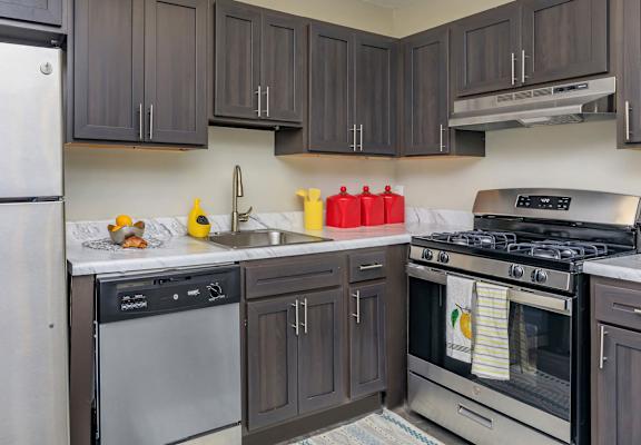 A modern kitchen with dark wood cabinets and stainless steel appliances. at Ashton Heights Apartments, Suitland, MD