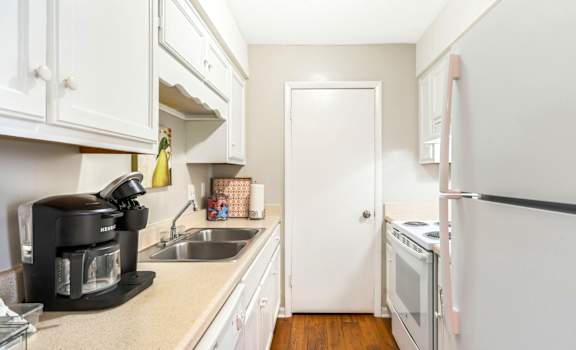 A kitchen with white cabinets and a black coffee maker.