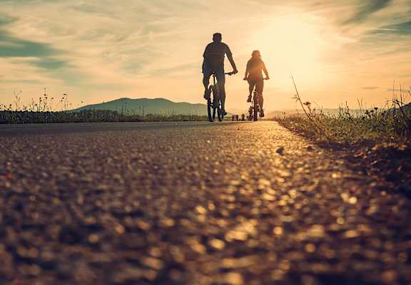A man and a child are riding bikes on a road.
