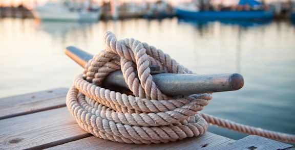 A rope tied in a knot rests on a wooden dock.