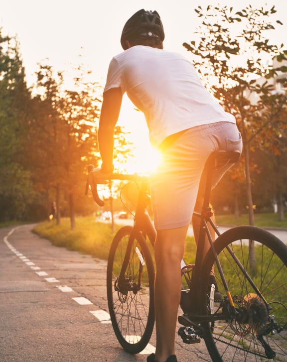 a man riding a bike down a road at sunset