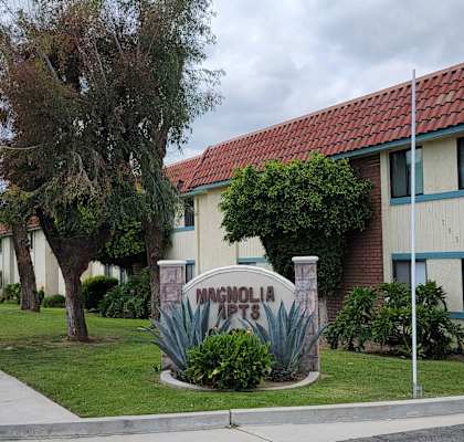 a sidewalk in front of a building with a sign in the middle of a grassy area