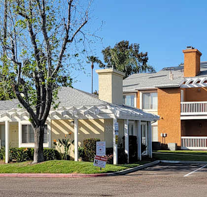 an apartment complex with a white canopy in front of a tree