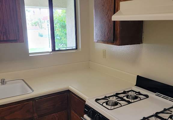 a kitchen with a white stove top oven next to a sink and a window