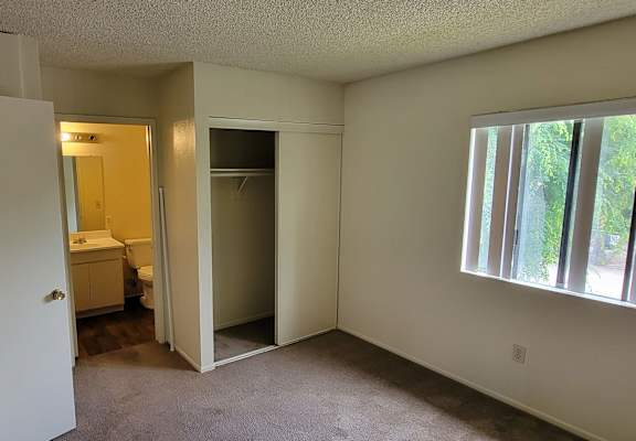 a bedroom with a large window and a bathroom in the background