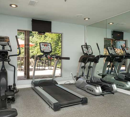 A room with a treadmill, elliptical trainer and a stationary bike.
