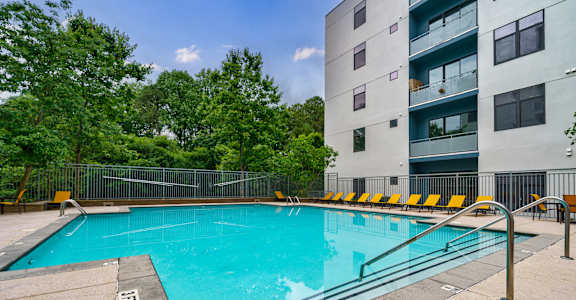 A swimming pool surrounded by a metal fence and yellow chairs.