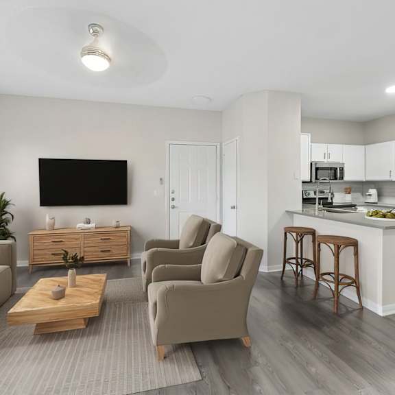 A modern living room with a grey sofa, a wooden coffee table, and a kitchen area in the background.