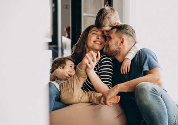 A family of three is sitting closely together on a couch.