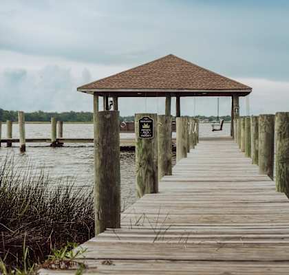 A wooden pier leads to a gazebo in the middle of a body of water.