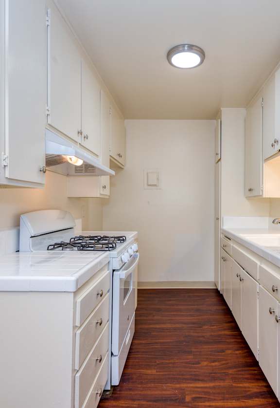 A white kitchen with a stove and sink.